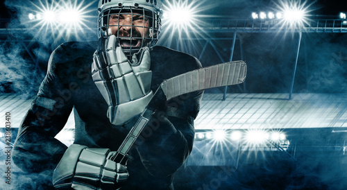 Photography Ice Hockey player in the helmet and gloves on stadium with stick.