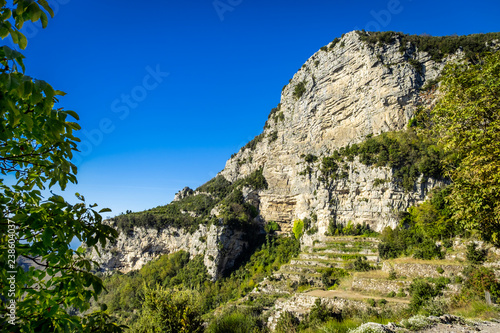 Rocky cliffs on Amalfi coast in Italy, covered green vegetation.