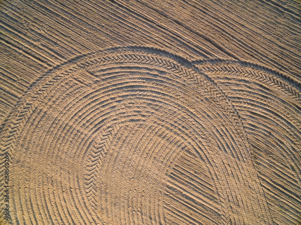 Fototapeta premium Aerial view of a plowland with harrow and tractor tires tracks, Poland