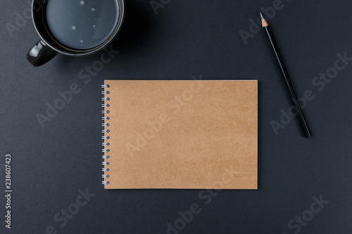 Blank notebook with pencil and Cup of coffee on black background. Workplace. Copy space. Minimal concept. Top view. Flat lay