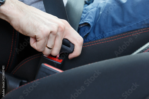 Men's hand fastens the seat belt of the car. Close up shot of male driver fastens seat belt
