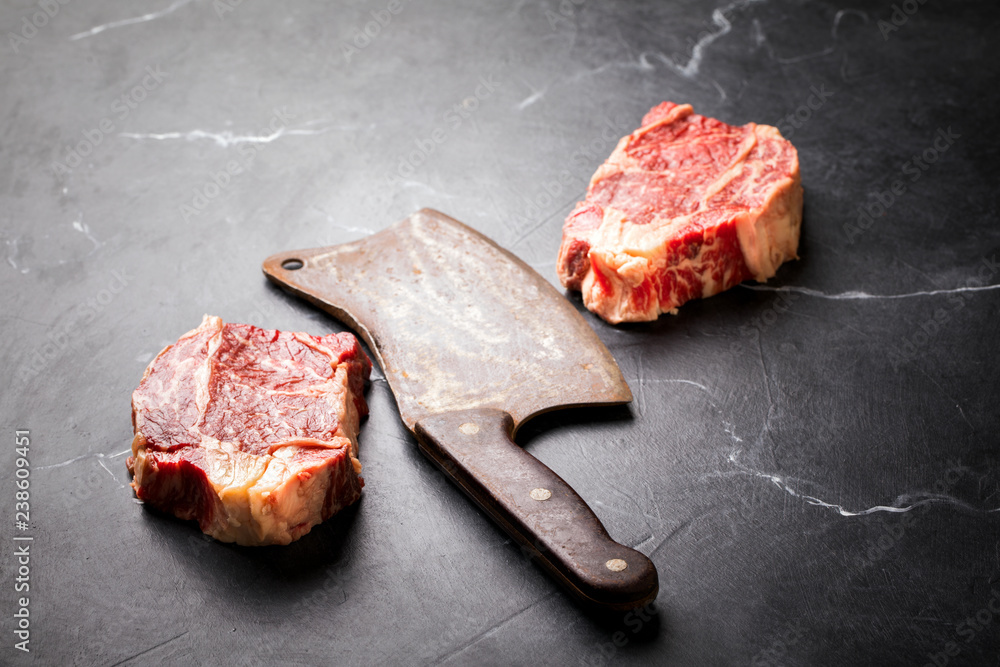 Raw Fresh Marbled Meat Beef Steak and and vintage ax  on a black background.Top View Copy space for Text