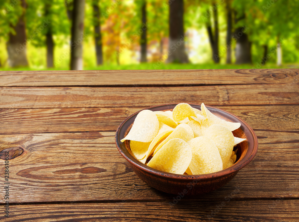 potato gold chips on plate wooden table on blurred park background potato gold chips on plate wooden table on blurred park background