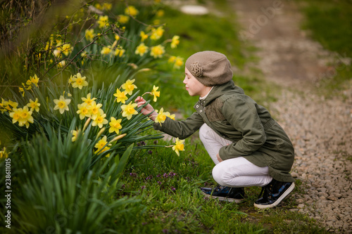Cute happy little girl in the spring country smelling yellow daffodils