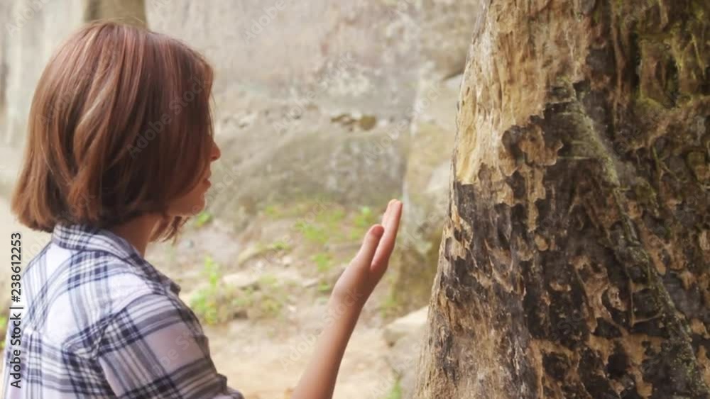 Nice teenage girl wearing in plaid shirt touching natural rock. Travelling concept, archeology. Summertime. Weekend. Outdoors. Nice teenage girl wearing in plaid shirt touching natural rock. Travelling concept, archeology. Summertime. Weekend. Outdoors.