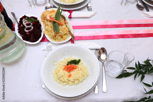 Makaron, marchewka i pietruszka na białym talerzu na stole weselnym.