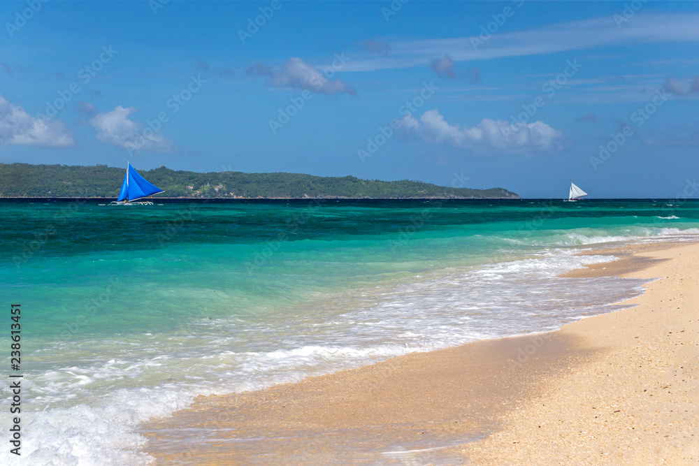 Small sailing boats passing by a white sand beach Small sailing boats passing by a white sand beach
