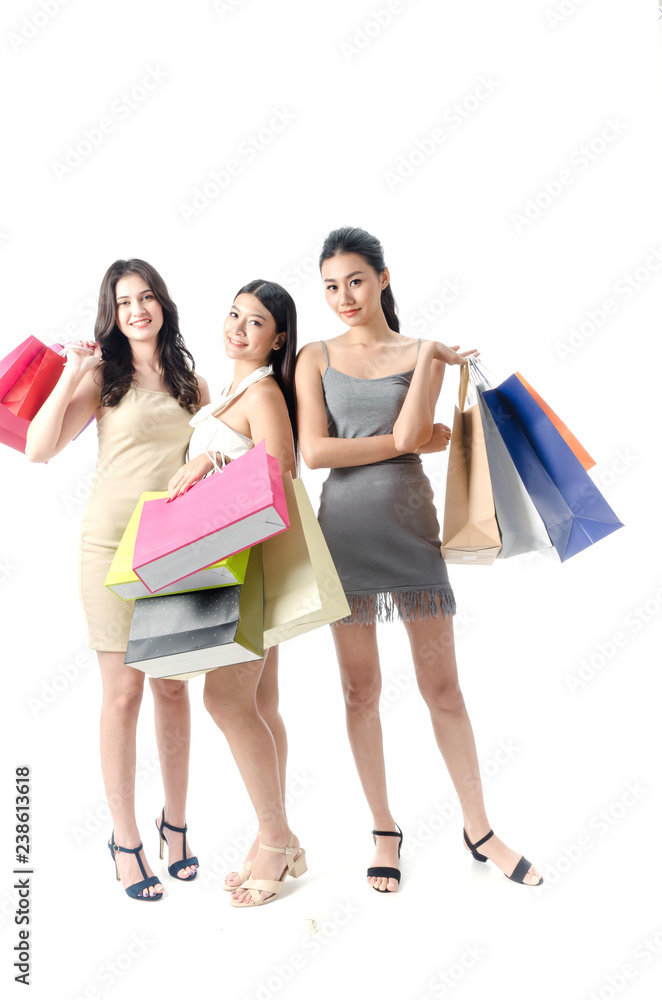 Portrait of three women holding colorful bags in raised hands enjoying seasonal sales isolated on white background