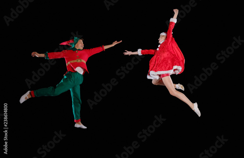 Christmas time, childhood, fairy tale. A young girl wearing a Santa's costume and boy wearing elf costume flying together photo