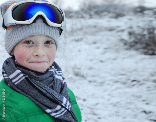 Cute happy boy skier on winter forest. Blurred background.
