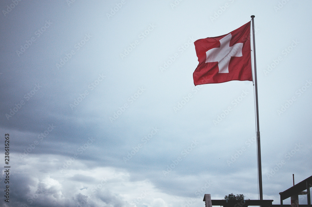 Flag of Switzerland waving in the wind on the mountain Chäserrugg. Popular tourist point. Travel to Switzerland Flag of Switzerland waving in the wind on the mountain Chäserrugg. Popular tourist point. Travel to Switzerland