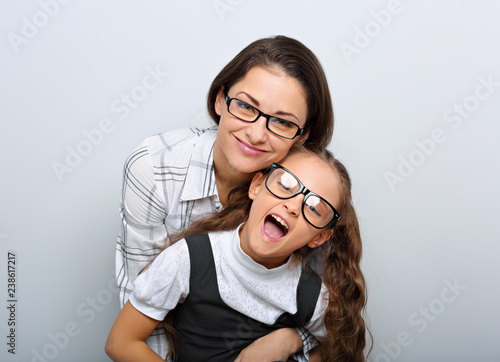 Happy young mother and lauging kid in fashion glasses hugging on empty copy space