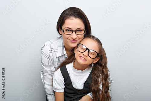 Happy young mother and lauging kid in fashion glasses hugging on empty copy space background. Family portrait