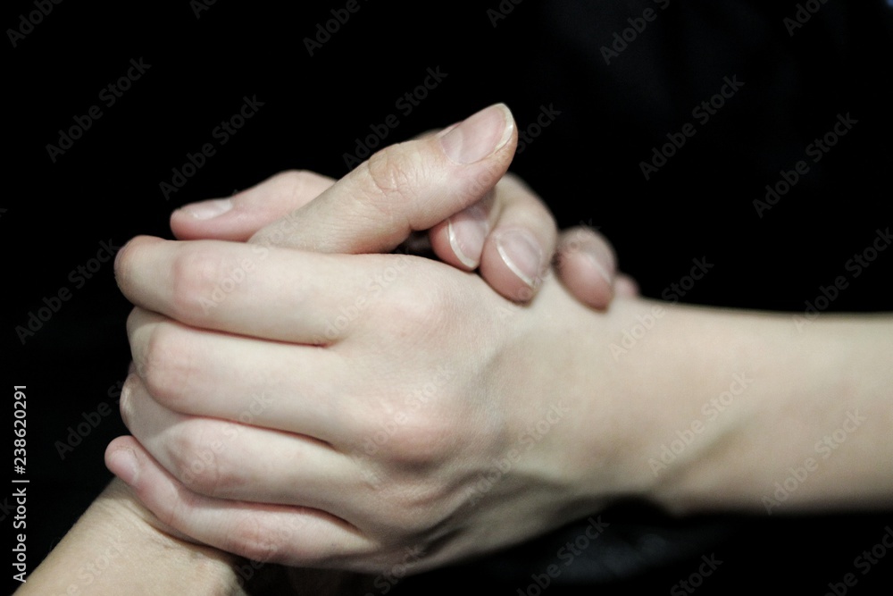 Holding out a helping hand, the hands of two people, one assisting the other, against a dark background