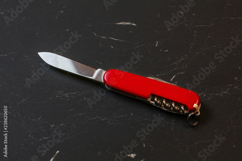 Red pocket knife on black table.