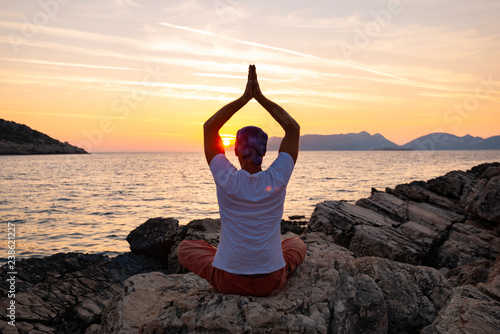 Male traveler practice yoga on the coastline