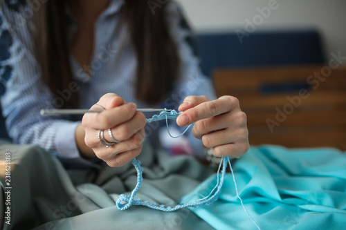 girl knits crochet from blue thread, designer