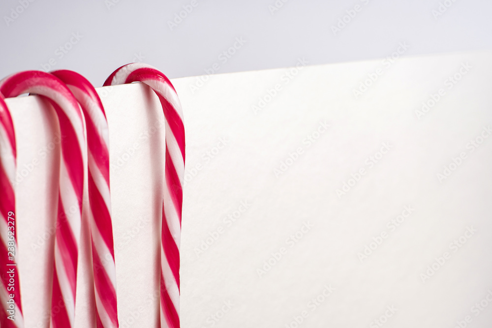 Fototapeta premium A few traditional christmas decoration candy canes hanging on a white surface