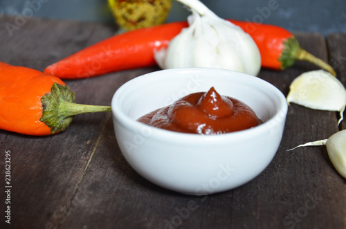 red hot sweet chilli sauce,ketchup over old wooden background with ingredients garlic ginger