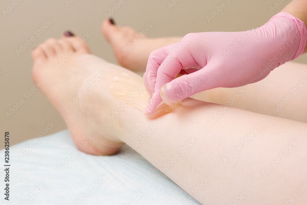 procedure of hair removing on leg beautiful woman with sugar paste or wax honey and pink gloves hand - depilation and beauty concept procedure of hair removing on leg beautiful woman with sugar paste or wax honey and pink gloves hand - depilation and beauty concept