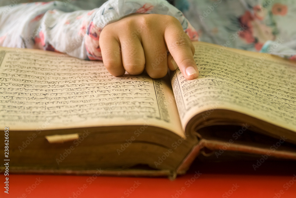 Fototapeta premium girl read the Koran while pointing to the verses she read