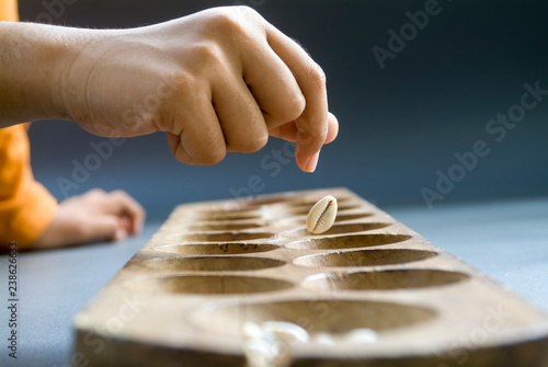 hand of a girl put shells into holes in the congklak game photo