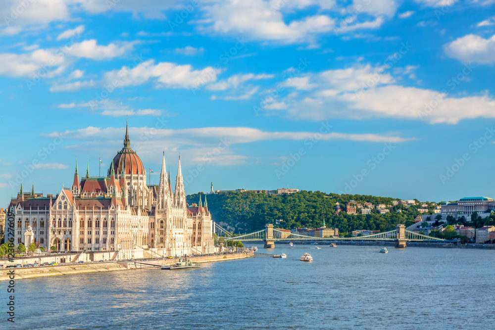 Travel and european tourism concept. Parliament and riverside in Budapest Hungary with sightseeing ships during summer sunny day with blue sky and clouds