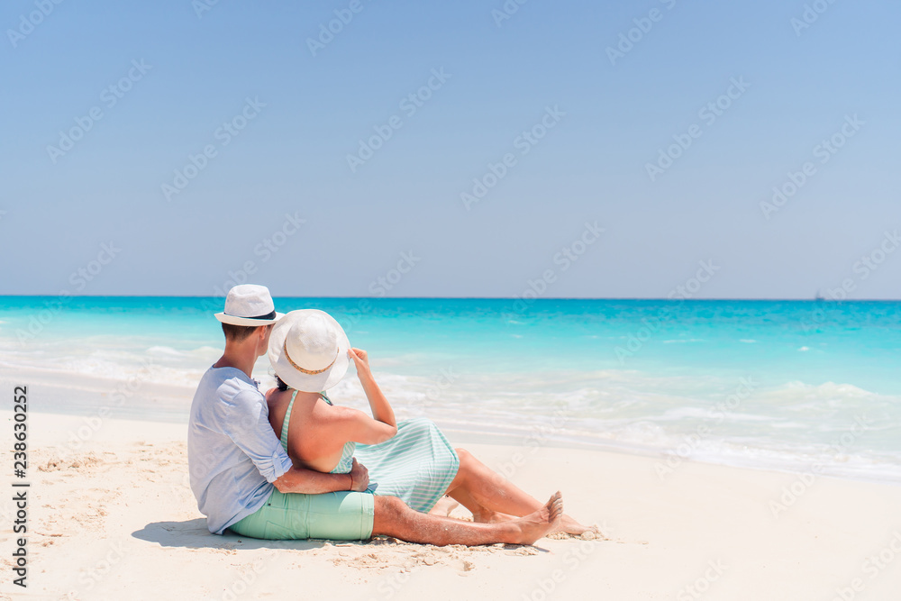Young couple on white beach during summer vacation. Happy lovers enjoy their honeymoon Young couple on white beach during summer vacation. Happy lovers enjoy their honeymoon