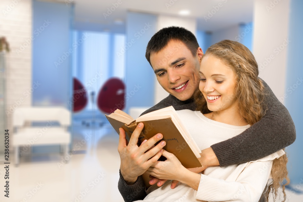 Happy Students reading a book in a library Happy Students reading a book in a library