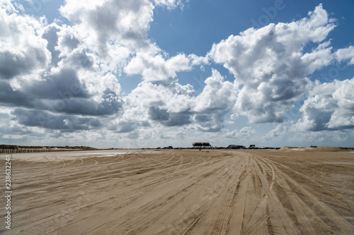 Cloudy sky over the broad sand road in Sankt Peter Ording, Germany at the Northern Sea coast. © Saga_bear