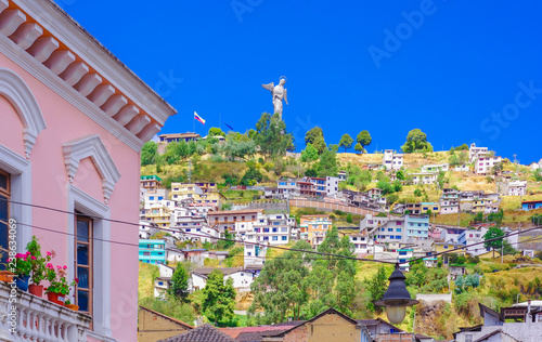Outdoor view of colonial buildings houses located in the city of Quito with the statue of Virgin of Panecillo in the background in gorgeous sunny day with blue sky