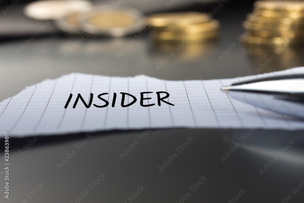 Insider auf einem Zettel mit Stift vor Geldmünzen Insider auf einem Zettel mit Stift vor Geldmünzen