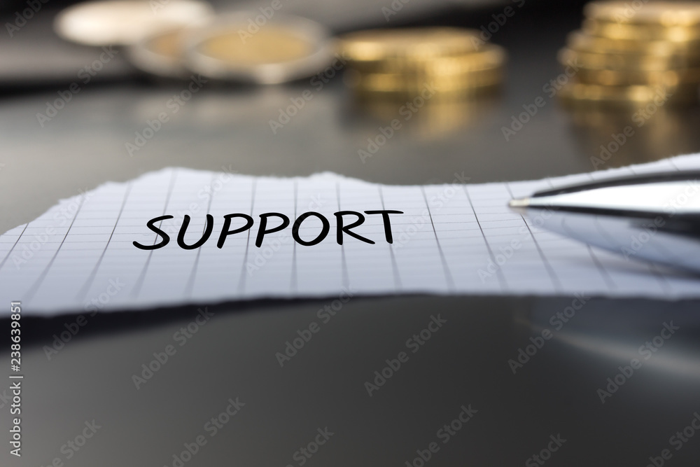 Support auf einem Zettel mit Stift vor Geldmünzen Support auf einem Zettel mit Stift vor Geldmünzen