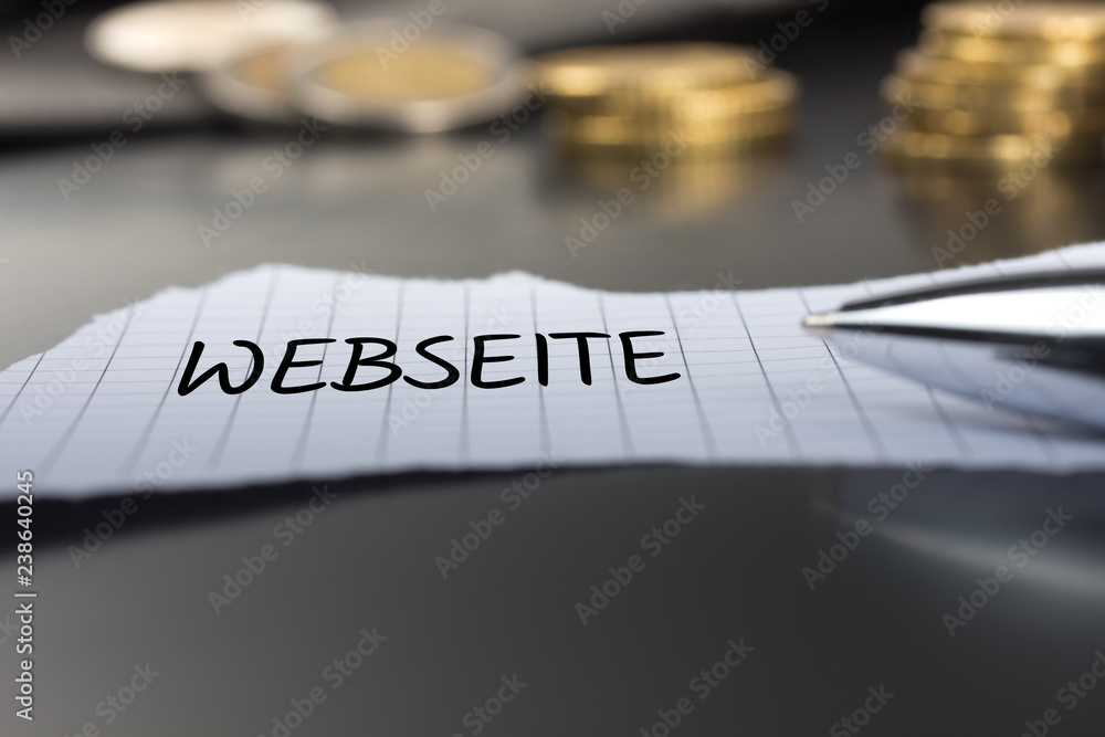 Webseite auf einem Zettel mit Stift vor Geldmünzen Webseite auf einem Zettel mit Stift vor Geldmünzen