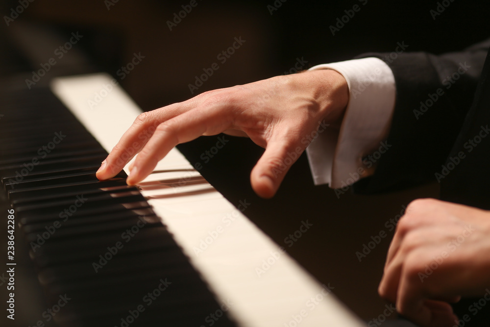Fototapeta premium Hands on piano. The pianist plays the piano. Piano keys on black background
