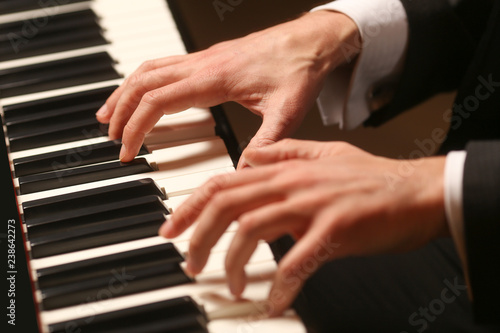 Hands on piano. The pianist plays the piano. Piano keys on black background