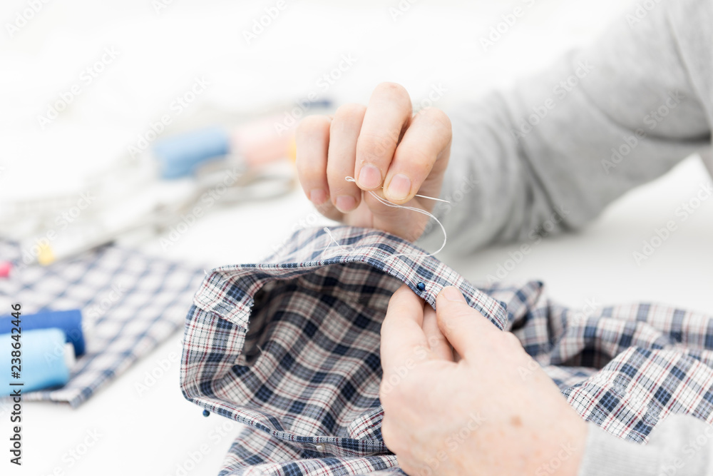 La costurera prepara la costura de un tejido con hilvanado