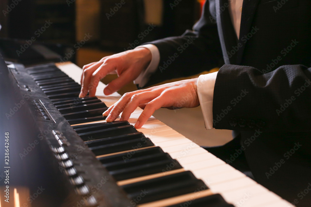 Fototapeta premium Hands on piano. The pianist plays the piano. Piano keys on black background