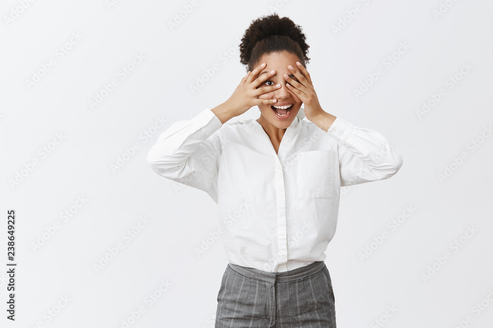 Time to play hide and seek. Portrait of joyful attractive and funny dark-skinned female entrepreneur having fun, being childish and carefree while playing peekaboo, peeking through fingers and smiling Time to play hide and seek. Portrait of joyful attractive and funny dark-skinned female entrepreneur having fun, being childish and carefree while playing peekaboo, peeking through fingers and smiling