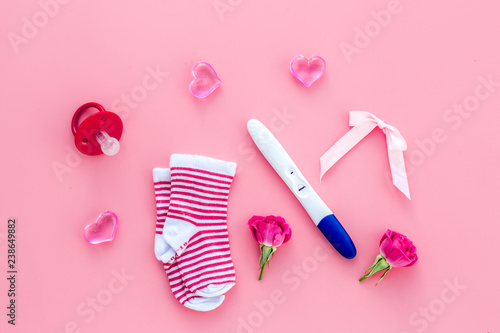 Pregnancy test, socks and hearts pink background top view