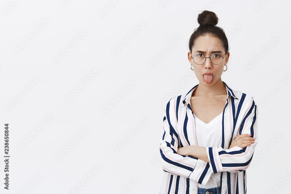 Moody girl showing character, expressing dislike, unwilling go home from party. Good-looking feminine woman in stylish shirt, holding hands crossed on chest and sticking out tongue childishly Moody girl showing character, expressing dislike, unwilling go home from party. Good-looking feminine woman in stylish shirt, holding hands crossed on chest and sticking out tongue childishly