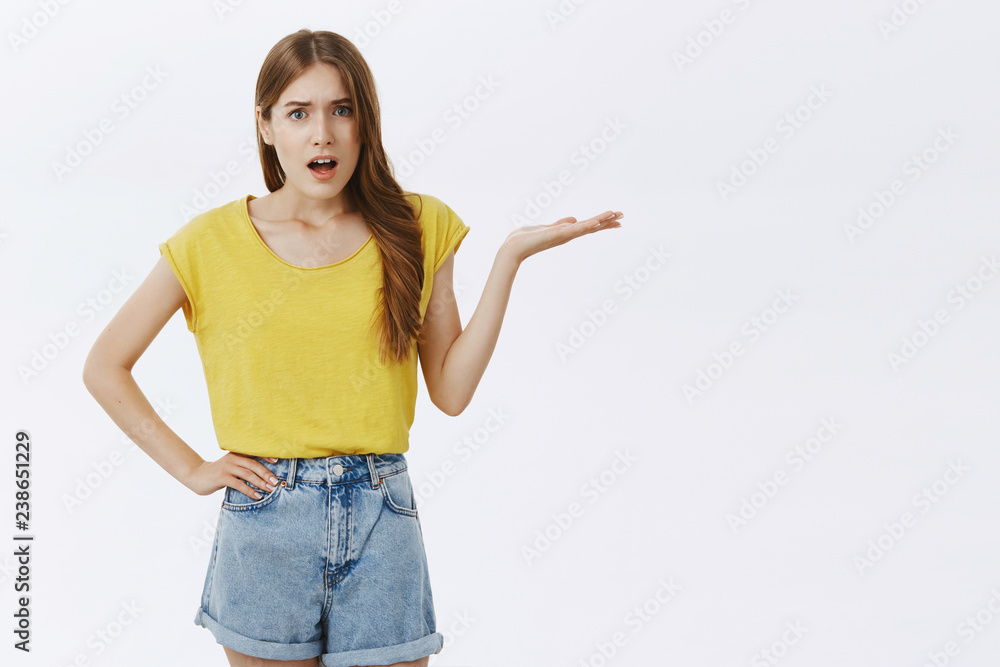 Girl complaining on boyfriend gesturing with raised palm standing questioned and bothered over gray background demanding explanation feeing confused and bothered against grey wall Girl complaining on boyfriend gesturing with raised palm standing questioned and bothered over gray background demanding explanation feeing confused and bothered against grey wall