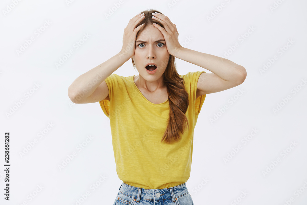 Girl having huge disaster on work feeling anxious and displeased holding hands on head in hopeless gesture opening mouth from surprise frowning standing dissatisfied and troubled over grey wall Girl having huge disaster on work feeling anxious and displeased holding hands on head in hopeless gesture opening mouth from surprise frowning standing dissatisfied and troubled over grey wall