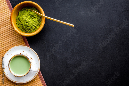 Coffee and cocktails with matcha concept. Matcha latte near bowl with matcha powder and accessories on black background top view copy space