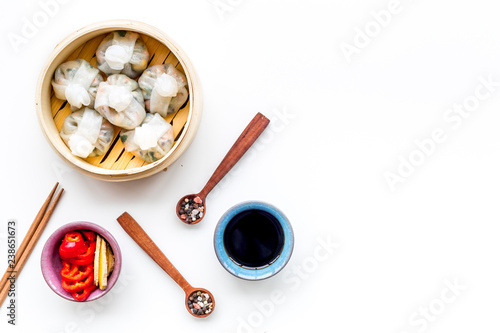 Chinese steamed dumplings Dim Sum with sweet paper and spices in bamboo steamer on white background top view mock up