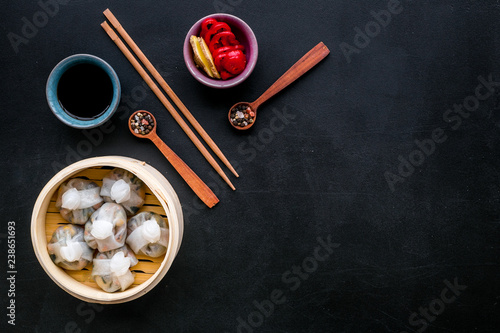 Chinese steamed dumplings Dim Sum with sweet paper and spices in bamboo steamer on black background top view mock up