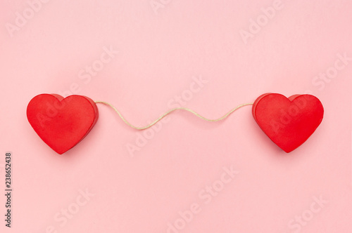Pair of red hearts connected with a string of twine