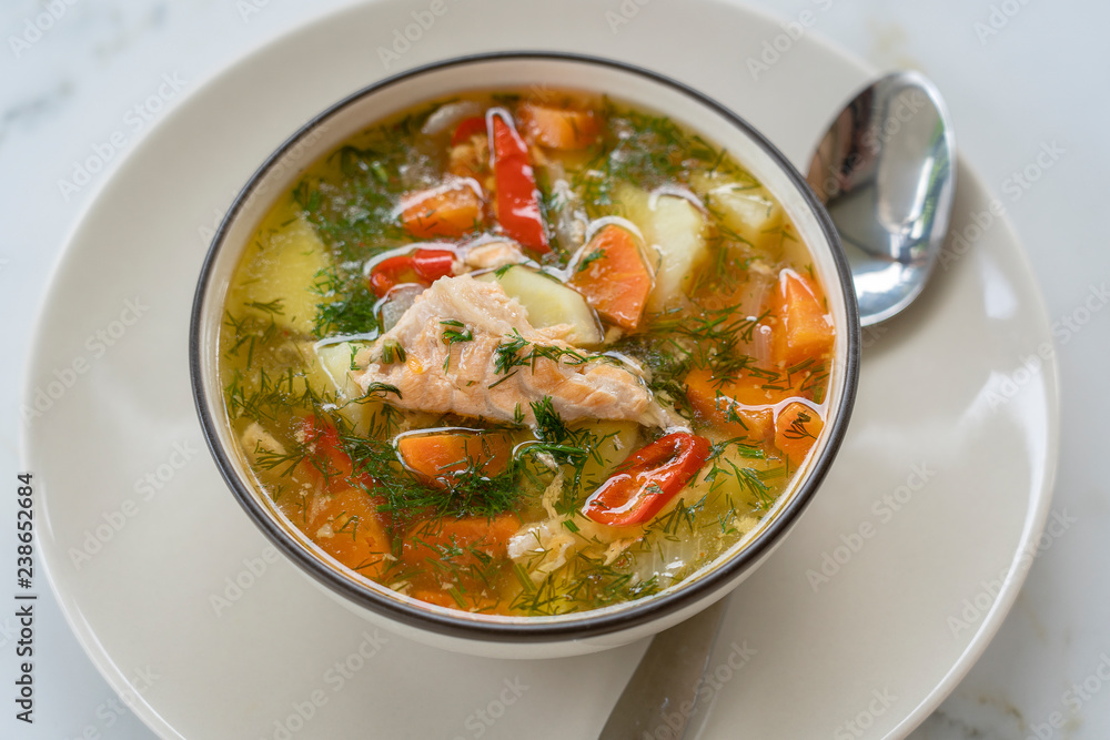 Salmon soup with potatoes, carrots, dill, pepper in bowl, close up Salmon soup with potatoes, carrots, dill, pepper in bowl, close up