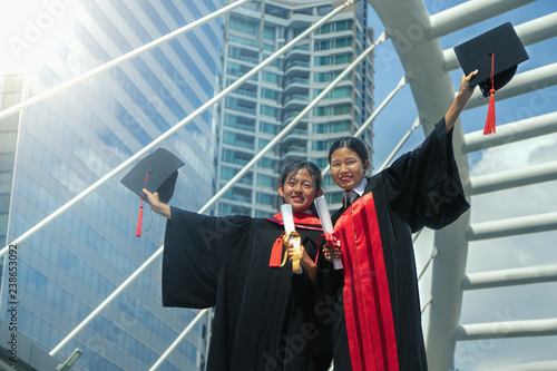 Asian female graduated students raise hand with cap up to celebrate the success