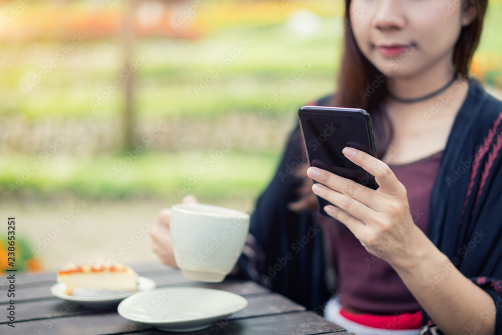 Beautiful Asian women have enjoyed in the garden with coffee and chatting in smartphone.. Beautiful Asian women have enjoyed in the garden with coffee and chatting in smartphone..